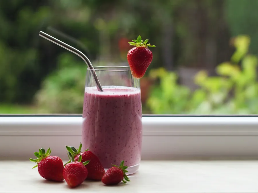Glas rode shake met aardbeien bij het raam