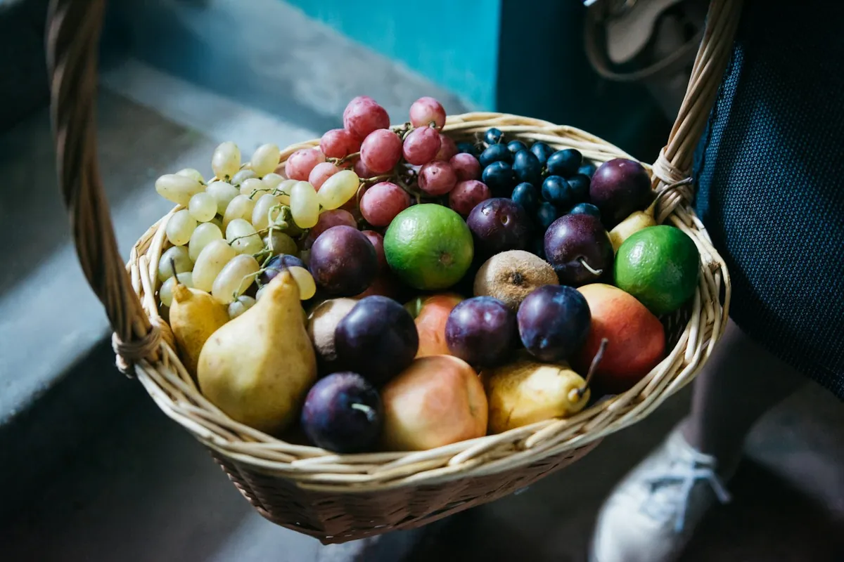 Rieten mand met druiven, peren, pruimen en appels