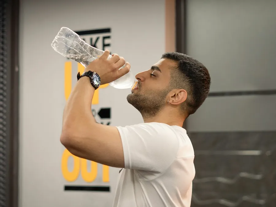 Man drinkt water uit een fles in de sportschool