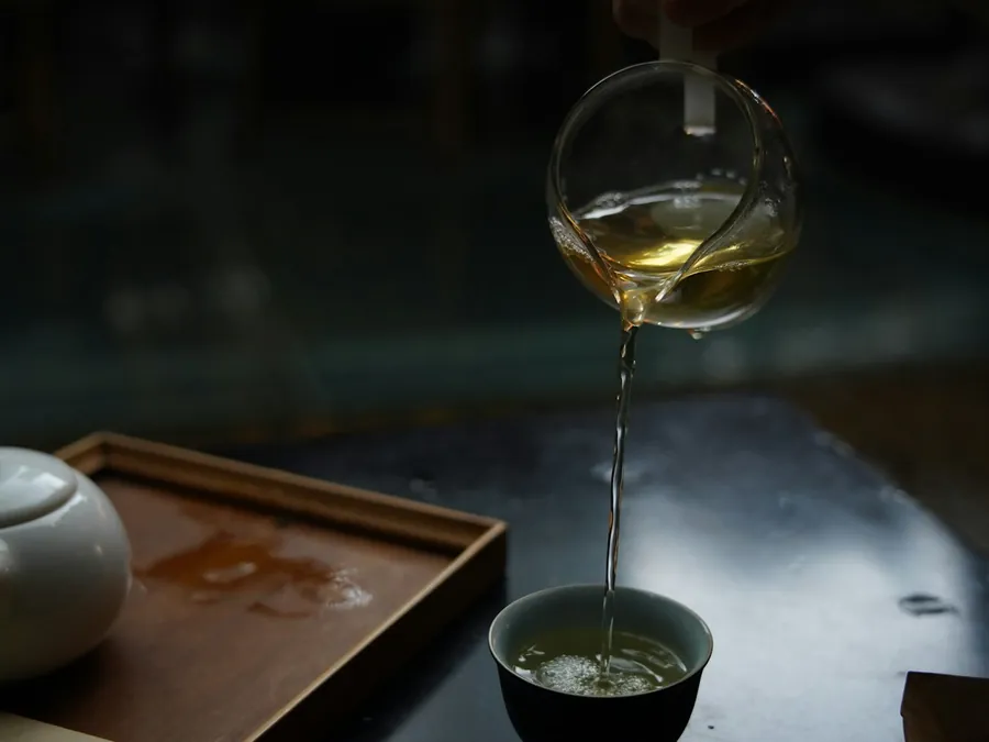 Groene thee wordt uit een glazen pot in een kopje geschonken